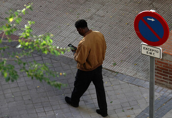 piel de color negro con tel&eacute;fono m&oacute;vil andando por la calle