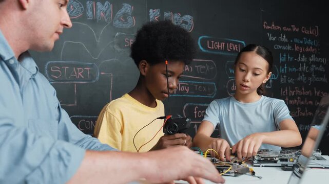 Young student fixing controller while teacher programming engineering code at STEM class. Closeup of instructor hand typing computer while smart girl using electronic tool and blackboard. Edification