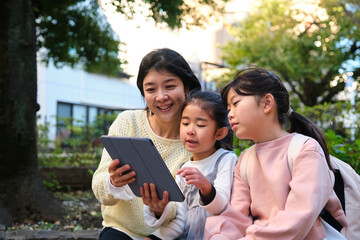 Japanese mother and daughters learning together using digital tablet