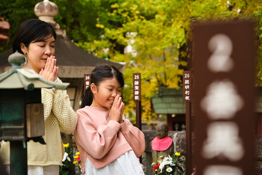 Japanese mother and daughter praying at temple