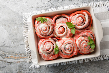 Freshly baked pink cinnabon buns with cream sauce in a baking dish on the table. Horizontal top view from above