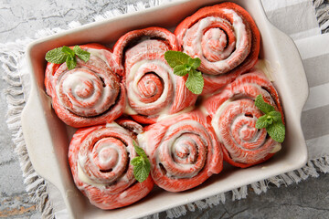Festive pink cinnabons, cinnamon rolls with white icing, close-up in a baking pan on a table. Horizontal top view from above