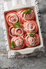 Homemade pink cinnamon rolls with cream cheese in a baking dish on the table. Vertical top view from above