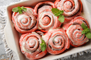 Festive pink cinnabon roll French buns with cinnamon and cream closeup on the plate on the table. horizontal top view from above