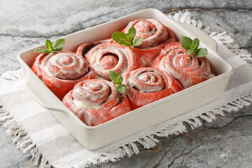 Freshly baked pink cinnabon buns with cream sauce in a baking dish on the table. Horizontal