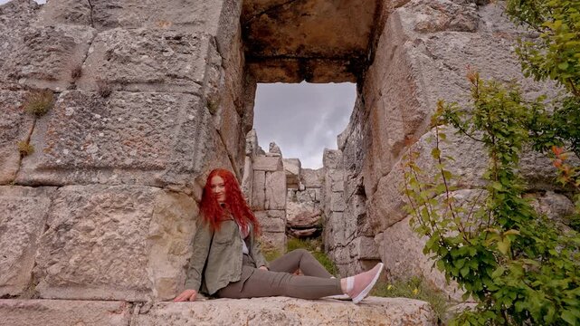 A female traveler resting among massive stone blocks and ancient gate ruins in Sagalassos Ancient City, Burdur, Turkey. Roman-era architecture reflecting archaeology, cultural heritage, travel and exp