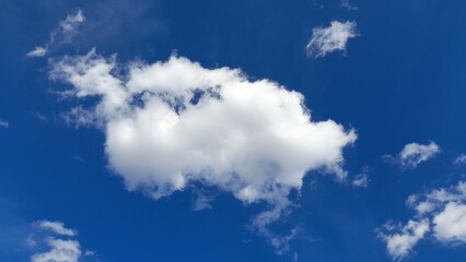 Single white fluffy cloud on a clear blue sky background.