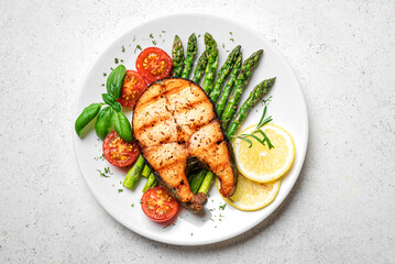 Grilled salmon fish steak with asparagus, tomatoes and lemon slices