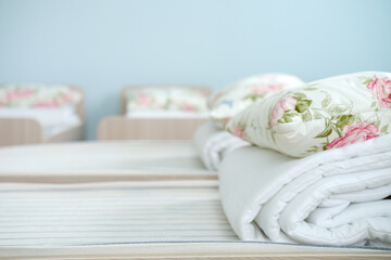 Children's beds with neatly arranged bed linen and decorative pillows in a bright orphanage room, creating a warm and inviting atmosphere for young residents