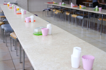 Long school canteen table set with colorful cups and plates, showcasing a clean and organized dining area, perfect for student meals and social gatherings