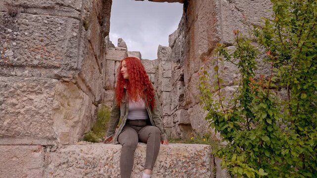 A female traveler resting among massive stone blocks and ancient gate ruins in Sagalassos Ancient City, Burdur, Turkey. Roman-era architecture reflecting archaeology, cultural heritage, travel and exp