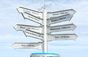 Directional signpost with multiple arrows indicating distances to various cities, showcasing travel options and wanderlust in a scenic outdoor setting