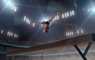 A gymnast performs a difficult trick on a balance beam.