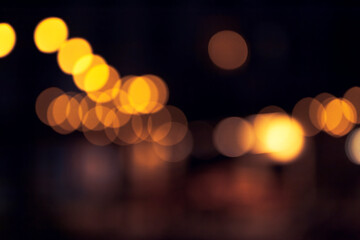 Defocused decorative lights form a diagonal flow of warm bokeh circles against a dark background.