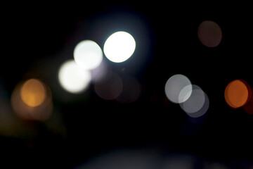 Defocused night lights form large circular bokeh shapes against a dark background. Bright white and