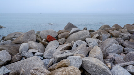 Wide view of a rocky tropical coastline facing open sea, featuring natural stone formations and tranquil ocean atmosphere.