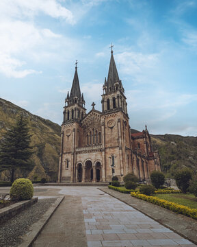 View of the majestic Basilica of Santa Mar&iacute;a la Real de Covadonga stands tall against a backdrop of rolling hills and a serene sky, Covadonga, Asturias, Spain.