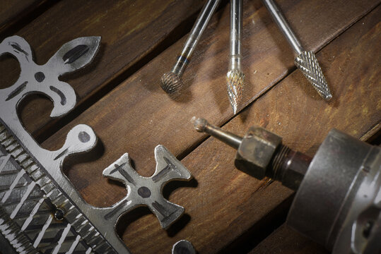 Electric straight grinder with metal milling cutter attachments for metalworking on wooden workbench table close up background.