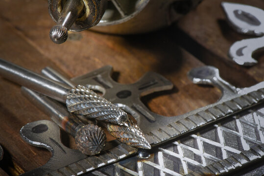 Electric straight grinder with metal milling cutter attachments for metalworking on wooden workbench table close up background.