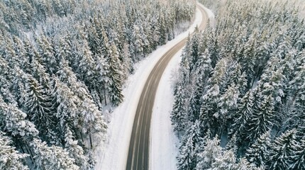 Aerial view of a road winding through a snow-covered winter forest