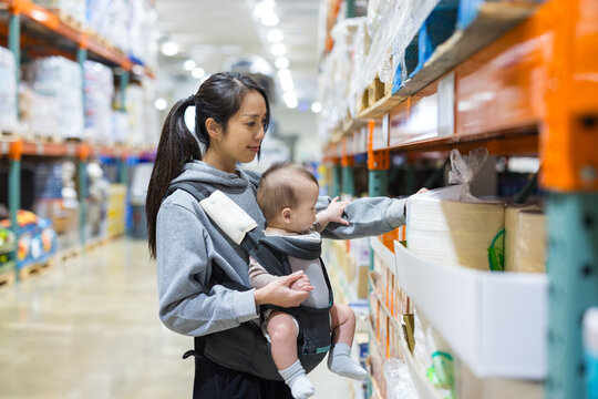 Mother carrying baby in supermarket shopping aisle