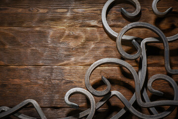 Forged metal scrollwork ornament decorative on dark wooden plank workbench table top view background.