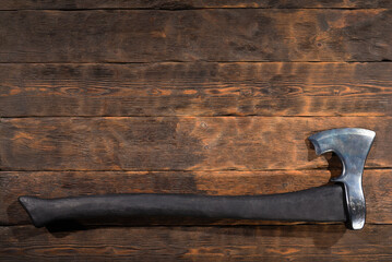 Forged steel axe with curved blade on wooden workbench table background. Top view.