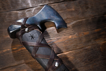 Forged steel axe with curved blade and leather wrapped handle engraved with runic symbols on wooden...