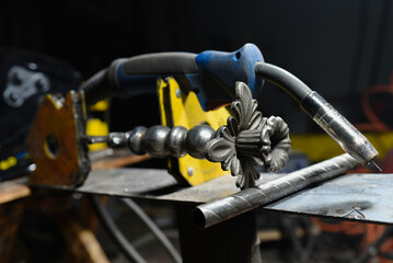 Floor standing wrought iron candelabra and electric welding torch concept during manufacturing process in blacksmith workshop.