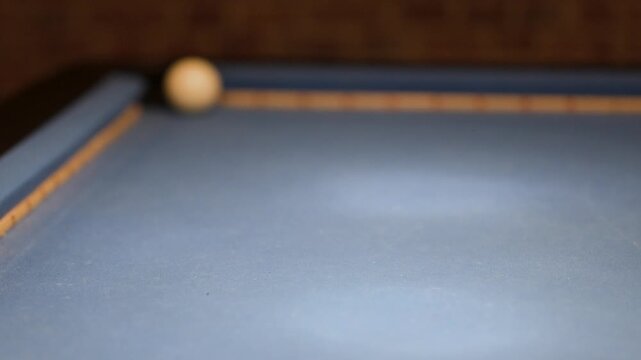 Cue Strikes Cue Ball on Billiard Table in Low Light