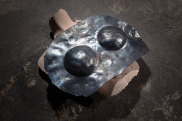 Forged steel armor bra with two hammered domed cups formed on clay mold during blacksmithing process on workshop floor background.