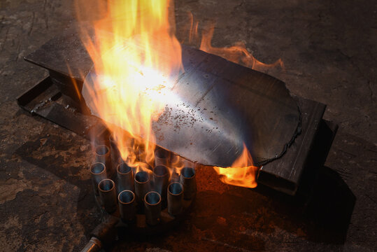 Metal plate heated by gas burners with open flame in blacksmith workshop on concrete floor background. - Powered by Adobe