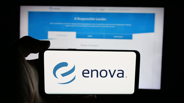 Stuttgart, Germany - 12-10-2025: Person holding cellphone with logo of US financial company Enova International Inc. on screen in front of webpage. Focus on phone display.