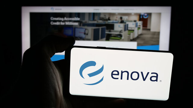 Stuttgart, Germany - 12-10-2025: Person holding mobile phone with logo of US financial company Enova International Inc. on screen in front of web page. Focus on phone display.