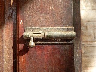 a photo of a hinge lock attached to a wooden door.
