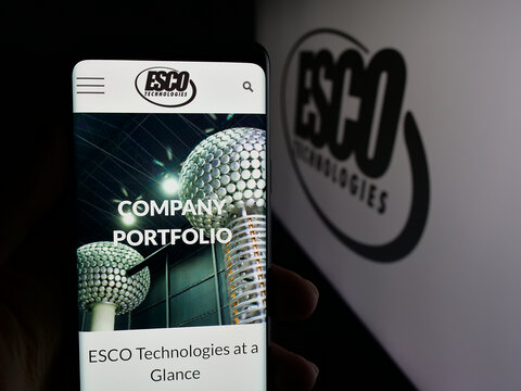 Stuttgart, Germany - 12-10-2025: Person holding smartphone with web page of US industrial company ESCO Technologies Inc. on screen in front of logo. Focus on center of phone display.