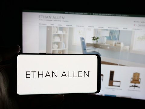 Stuttgart, Germany - 12-10-2025: Person holding smartphone with logo of furnishing company Ethan Allen Interiors Inc. on screen in front of website. Focus on phone display.