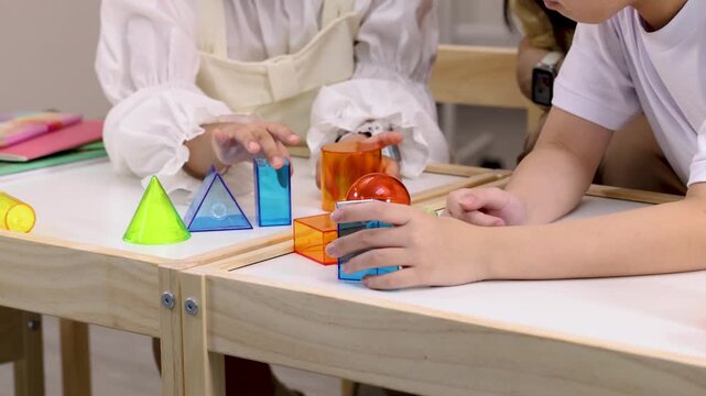 Teacher and child building colorful geometric shapes in classroom