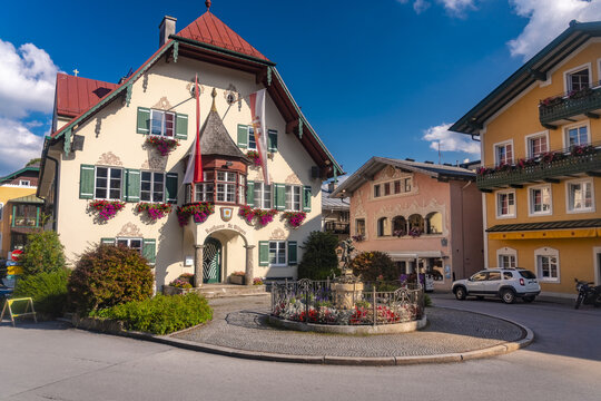 View of a picturesque town square with traditional buildings adorned with colorful flower boxes, centered around a charming fountain, Saint Gilgen, Salzburg, Austria.