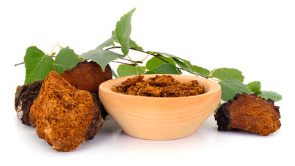 Chaga mushroom in wooden bowl with birch branch isolated on white