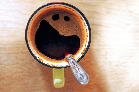 Pareidolia cup of black coffee with funny crazy smile