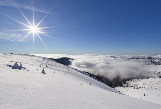 View of a crisp, snow-blanketed landscape under a radiant sun, with a sea of clouds rolling towards the horizon, Nizke Tatry, Banska Bystrica Region, Slovakia.