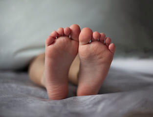 Close-up of baby's feet. Cute little baby lying on bed. Child resting