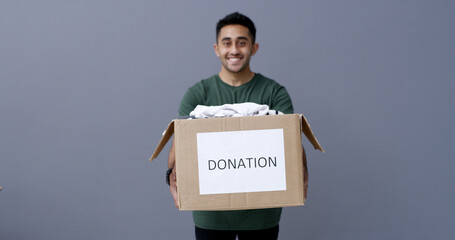 Happy man, portrait and box with donation in studio for charity or welfare on a gray background....