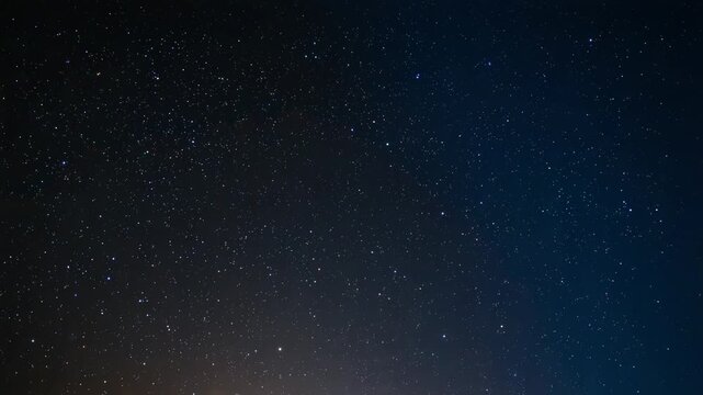 Recording time passing, starry night sky shifting over low horizon, warm glow brightening