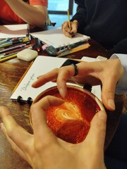 Hands creating latte art in a cozy cafe setting
