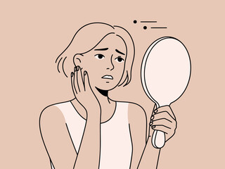Woman Examining Acne in Mirror