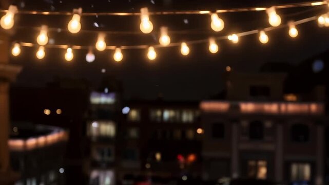 Projecting decorative snowflakes drifting across nighttime urban balcony, with warm string lights