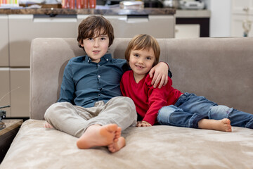 Two brothers relaxing on sofa at home