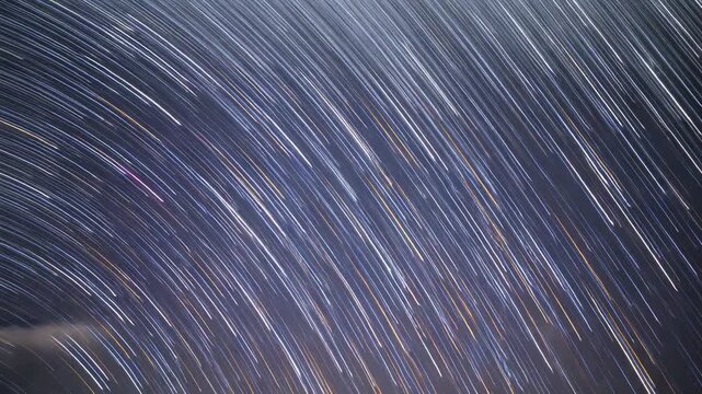 Starting exposure, camera capturing star trails forming over night sky to show rotation, with cloud